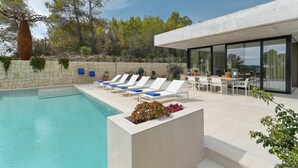 Area piscina esterna moderna con sedie a sdraio e un tavolo da pranzo.