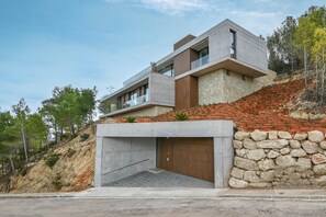 A modern two-story house with a stone retaining wall, a garage, and a hillside backdrop. - Casa de Romero 6 pax - Javea, Costa Blanca (Javea)