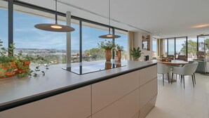 Una cucina moderna con una grande isola, illuminazione a sospensione e vista sulla città.