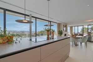 A modern kitchen with a large island, pendant lighting, and a view of the cityscape. - Casa de Romero 6 pax - Javea, Costa Blanca (Javea)