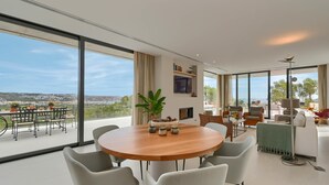 Un'area pranzo moderna con un tavolo grande e sedie, una pianta in vaso e vista su un balcone con posti a sedere esterni.
