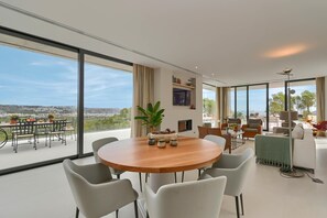 A modern dining area with a large table and chairs, a potted plant, and a view of a balcony with outdoor seating. - Casa de Romero 6 pax - Javea, Costa Blanca (Javea)
