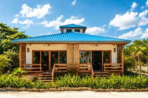 A two-story building with a blue roof, large glass windows, and a wooden deck. - Beachfront Estate Scenic Private (San Pedro)