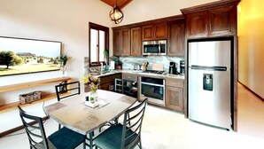 Una cocina moderna con armarios de madera, electrodomésticos de acero inoxidable y un comedor con mesa y sillas.