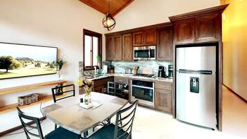 A modern kitchen with wooden cabinets, stainless steel appliances, and a dining area with a table and chairs.