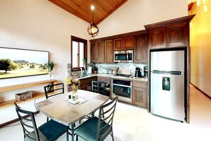 A modern kitchen with wooden cabinets, stainless steel appliances, and a dining area with a table and chairs. - Beachfront Estate Scenic Private (San Pedro)