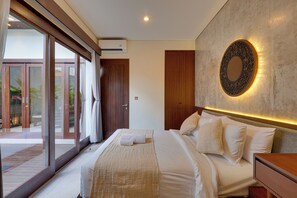 Habitación de hotel con una cama grande, un espejo fijado a la pared y un ventanal corredizo que da a un espacio exterior.