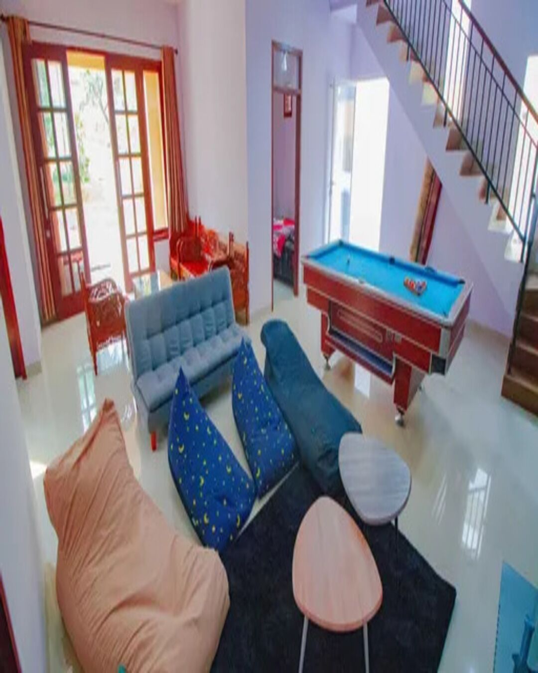 A living room with a sofa, a pool table, and a staircase.