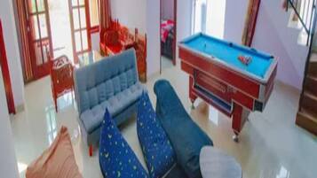 A living room with a sofa, a pool table, and a staircase.