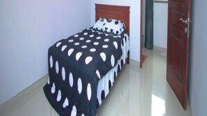 Un dormitorio con una cama, una puerta de madera y una ventana.