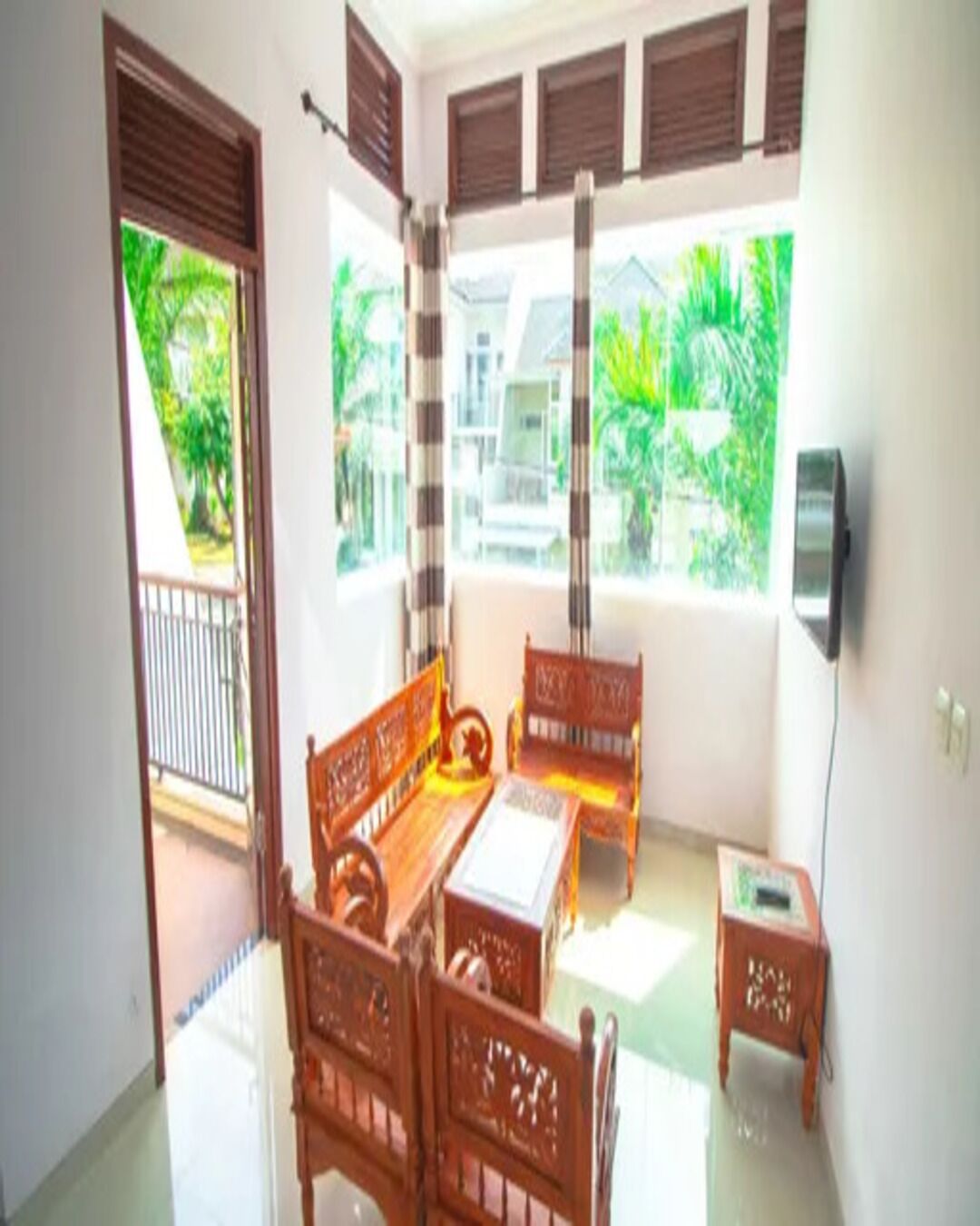 A room with a wooden bench, a table, and a TV on the wall.