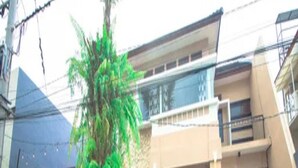 Un edificio residencial con entrada principal, balcón y pequeño jardín.
