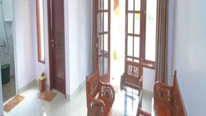 Una habitación con una mesa y sillas de madera, una puerta y una ventana con cortinas.