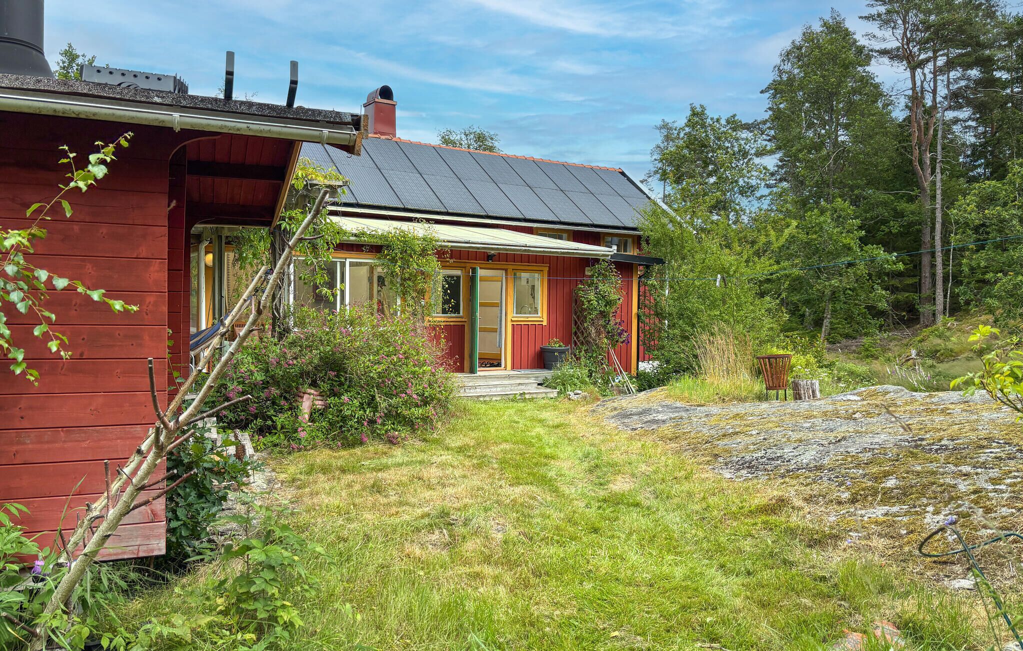 A red wooden house with a sloped roof, a chimney, and a small porch.