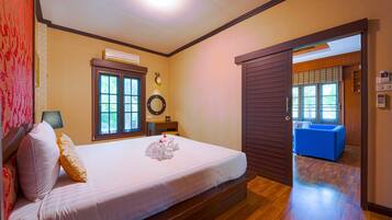 A hotel room with a bed, a desk, a mirror, and a view of the outside.