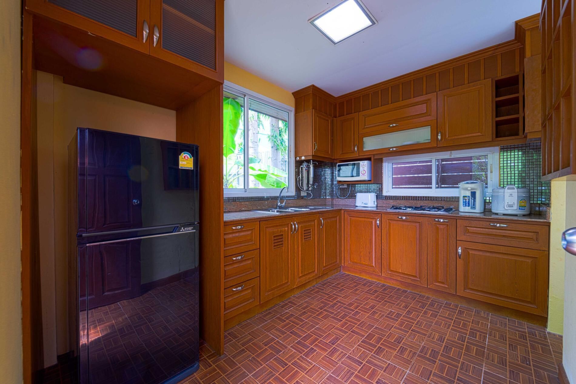 A kitchen with wooden cabinets, a refrigerator, a microwave, and a stove.