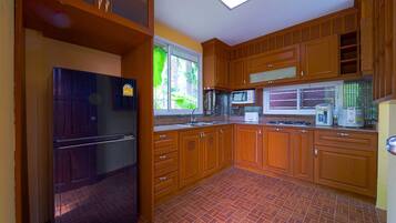 A kitchen with wooden cabinets, a refrigerator, a microwave, and a stove.