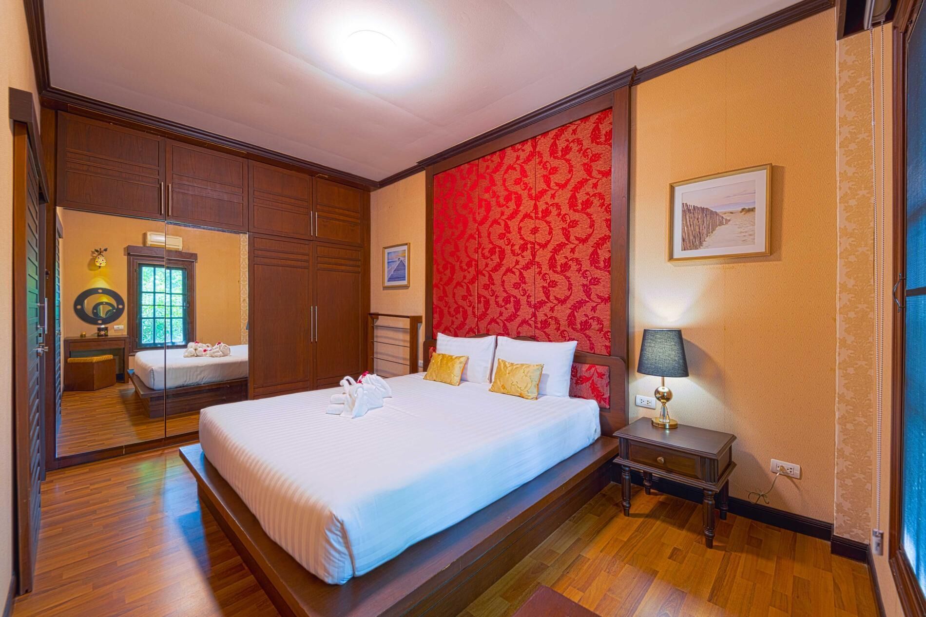 A hotel room with a large bed, a nightstand, a lamp, and a mirror.