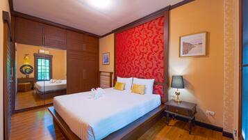 A hotel room with a large bed, a nightstand, a lamp, and a mirror.