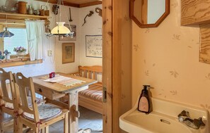 A cozy room with a wooden table, chairs, a bed, a hanging light fixture, and a wall-mounted mirror. - 1 bedroom lovely home in Leksand (Leksand)