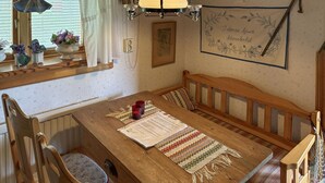 Een gezellige eethoek met een houten tafel, bankjes en een kamerkleed met een patroon.