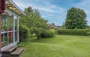 A well-maintained lawn with a wooden bench, a glass-enclosed structure, and a large tree in the background. - 1 bedroom lovely home in Leksand (Leksand)