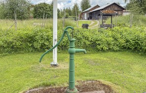 A green, old-fashioned water pump in a grassy area with a wooden house in the background. - 1 bedroom lovely home in Leksand (Leksand)