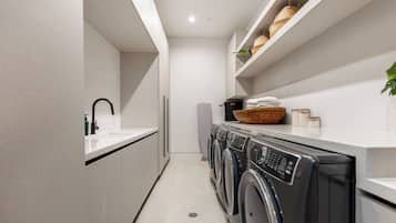 A modern laundry room with a washing machine, dryer, and a sink.
