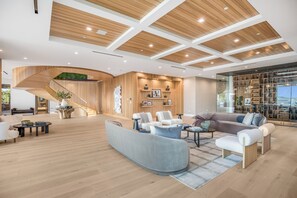A spacious living area with a curved sofa, a coffee table, and a staircase with a wooden finish.