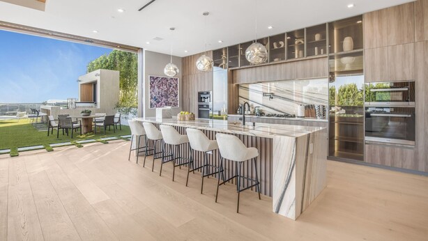 A modern kitchen with a large island, bar stools, and stainless steel appliances.
