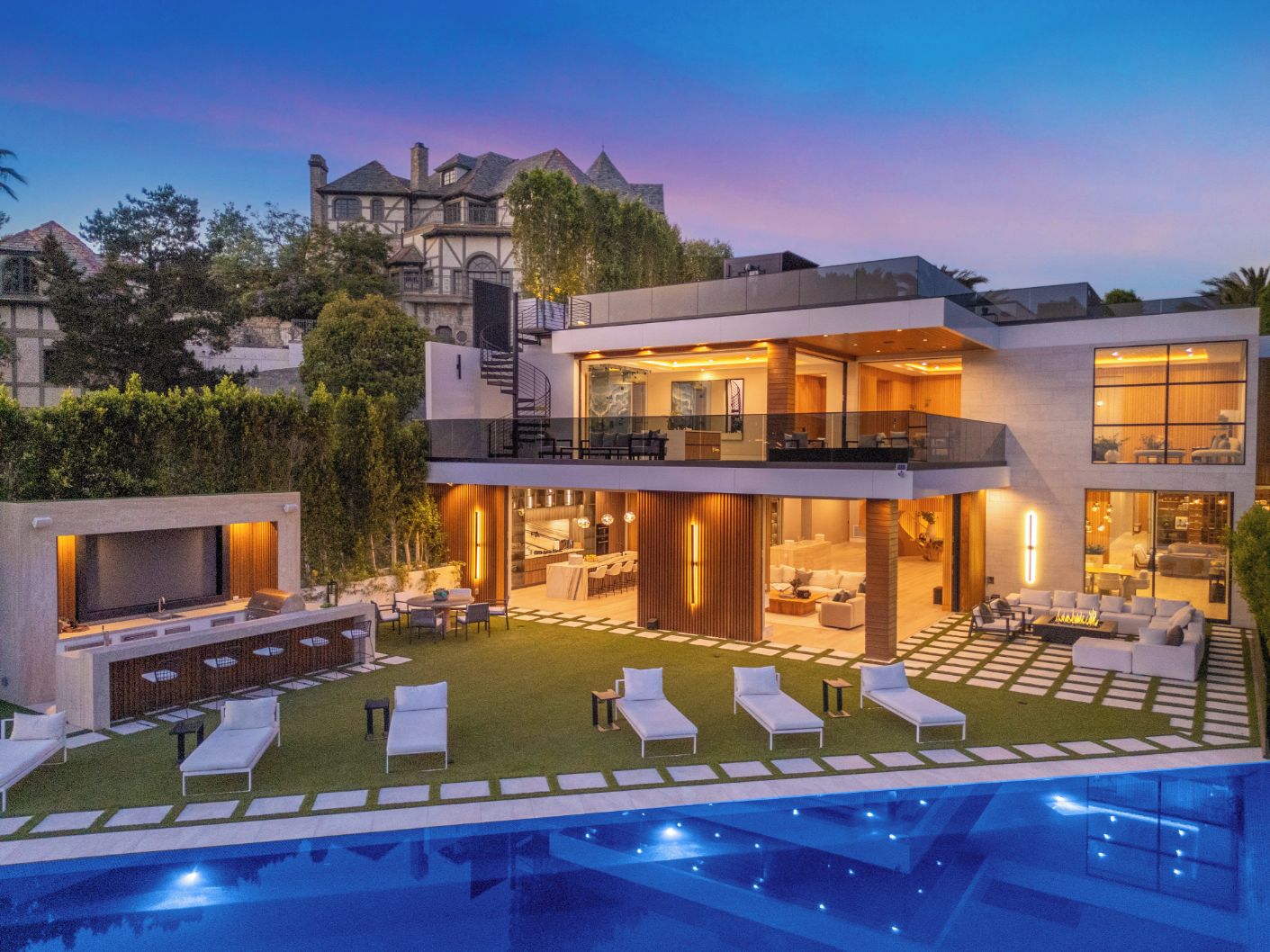 Una casa moderna de dos pisos con un amplio patio exterior, piscina y un interior bien iluminado.