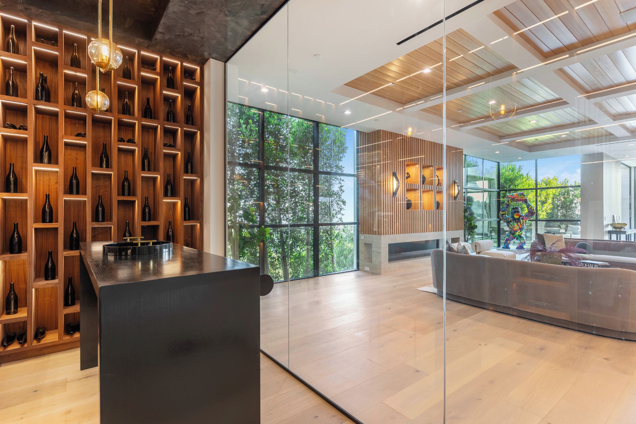 A modern interior with a wine cellar, large windows, and a cozy seating area.