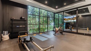 A modern gym with large windows, exercise equipment, and a TV.