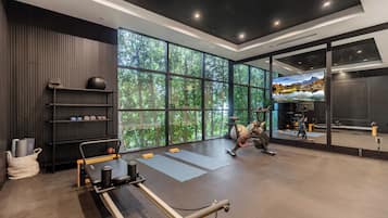 A modern gym with large windows, exercise equipment, and a TV.