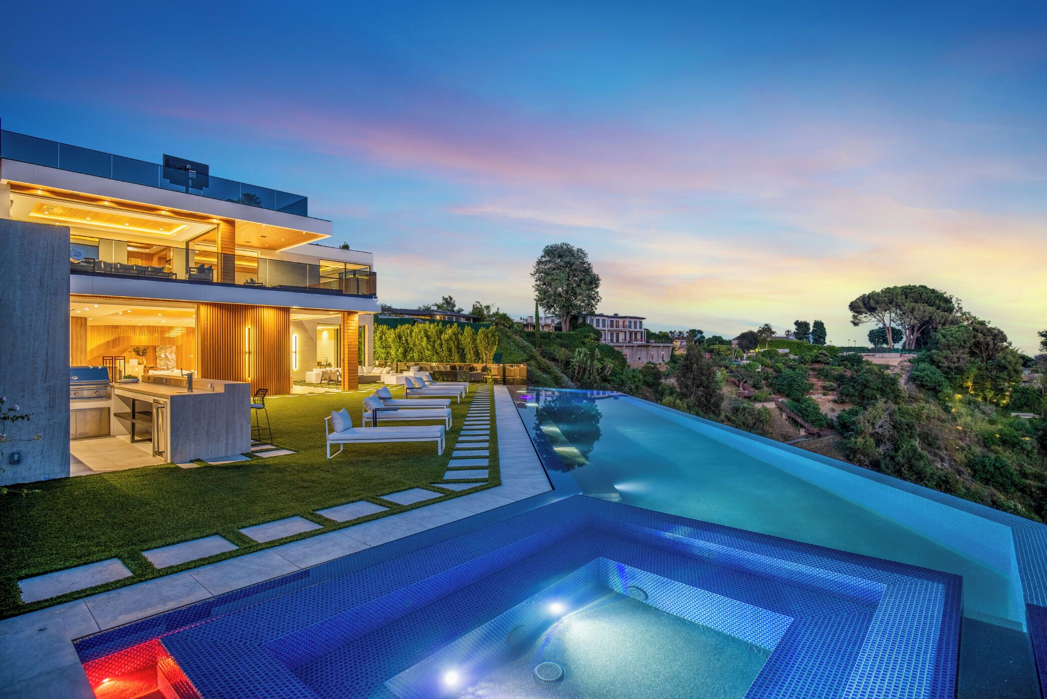 A modern house with a large swimming pool, outdoor seating, and a well-maintained garden.