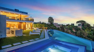 A modern house with a large swimming pool, outdoor seating, and a well-maintained garden.