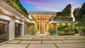 A modern house with a spacious patio, a wooden deck, and a well-maintained garden.