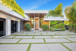 A modern building with a central entrance, surrounded by a garden with a geometric stone pathway.