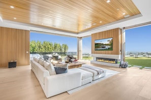 A modern living room with a large sofa, a fireplace, and a TV. - Somera Masterpiece (Los Angeles)