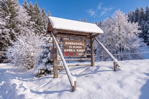 A wooden signpost with a snow-covered roof, surrounded by snow-laden trees. - Alpine Lodge Goska Ravan Rooms (Radovljica)