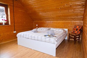 A wooden cabin bedroom with a bed, a chair, and a window. - Alpine Lodge Goska Ravan Rooms (Radovljica)