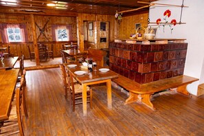 A wooden interior with a dining area, wooden benches, and a wall-mounted display. - Alpine Lodge Goska Ravan Rooms (Radovljica)