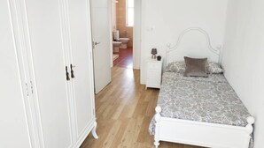 Quarto com cama, mesa de cabeceira, luminária e armário.