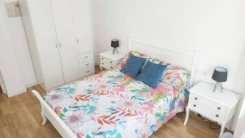 Un dormitorio con una cama, dos mesitas de noche, un armario y una mesilla.