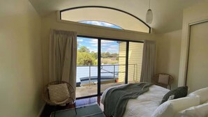 A bedroom with a bed, a chair, a window, and a view of the outdoors. - Halls Gap Escape Townhouse 4 (Halls Gap)