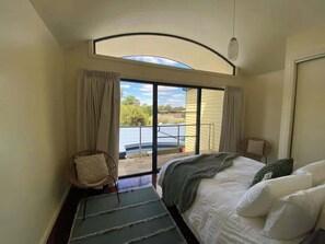 Ein Schlafzimmer mit Bett, Stuhl, Fenster und Blick ins Freie.