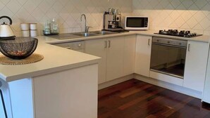 A modern kitchen with white cabinetry, a microwave, stove, and a sink. - Halls Gap Escape Townhouse 4 (Halls Gap)
