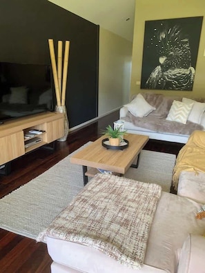 A living room with a flat-screen TV, a wooden coffee table, a sofa, and a painting on the wall. - Halls Gap Escape Townhouse 4 (Halls Gap)