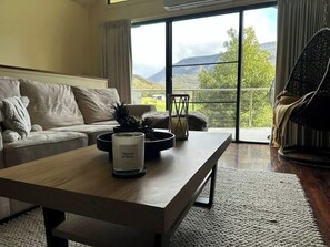 Een moderne woonkamer met een bank, een bijzettafeltje met een kaars, en uitzicht op de omgeving.
