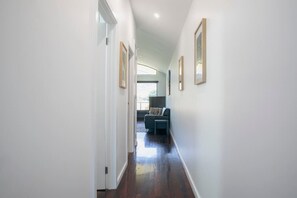 A hallway with a sofa and a coffee table, white walls, and framed pictures. - Halls Gap Escape Townhouse 6 (Halls Gap)